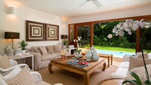 A spacious living room with a large window, a ceiling fan, and a pool visible through the glass doors. - Claro de Luna by Casa de Campo Resort & Villas (La Romana)
