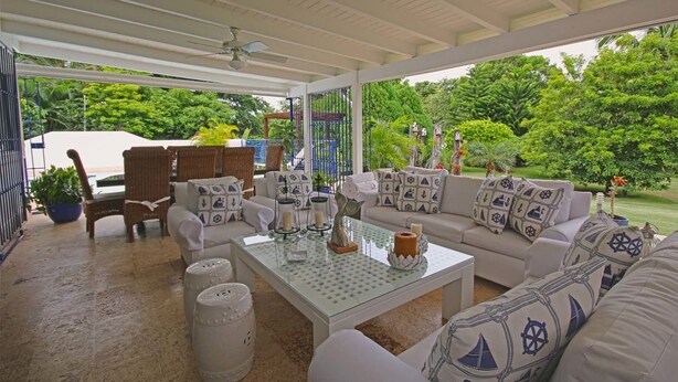 A covered outdoor seating area with wicker furniture, a glass-top coffee table, and nautical-themed cushions. - Casa del Rocio by Casa de Campo Resort & Villas (La Romana)