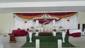 A stage with a green carpet, white pillars, and red drapes. - Akagera Resort and Country Club (Rwimbogo)