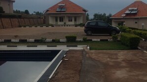 A residential area with a swimming pool, a paved driveway, and two houses with red-tiled roofs. - Akagera Resort and Country Club (Rwimbogo)
