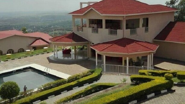 A two-story house with a red roof, a swimming pool, and a well-maintained garden. - Akagera Resort and Country Club (Rwimbogo)