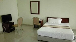 A hotel room with a bed, two chairs, a desk, a television, and a mirror on the wall. - Akagera Resort and Country Club (Rwimbogo)