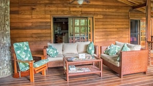 L’intérieur d’un chalet en bois, avec un canapé, deux fauteuils, une table basse et un ventilateur de plafond.