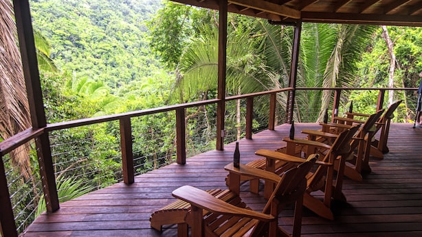 Une terrasse en bois, agrémentée de chaises, qui offre une vue imprenable sur une forêt verdoyante.