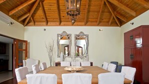 A dining room with a wooden table, white chairs, and a chandelier.