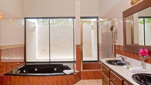 A bathroom with a bathtub, a sink, a mirror, and a window.