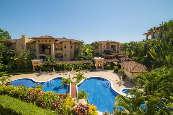 Relax by the resort's central pool surrounded by lush greenery and palm trees.