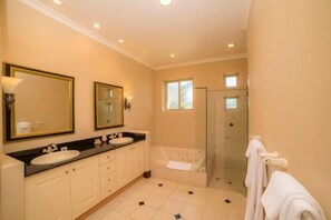 Bathroom features two sinks, a bathtub, and a glass-enclosed shower area.