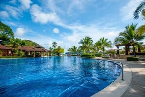 Relax by the serene pool surrounded by lush greenery and palm trees.