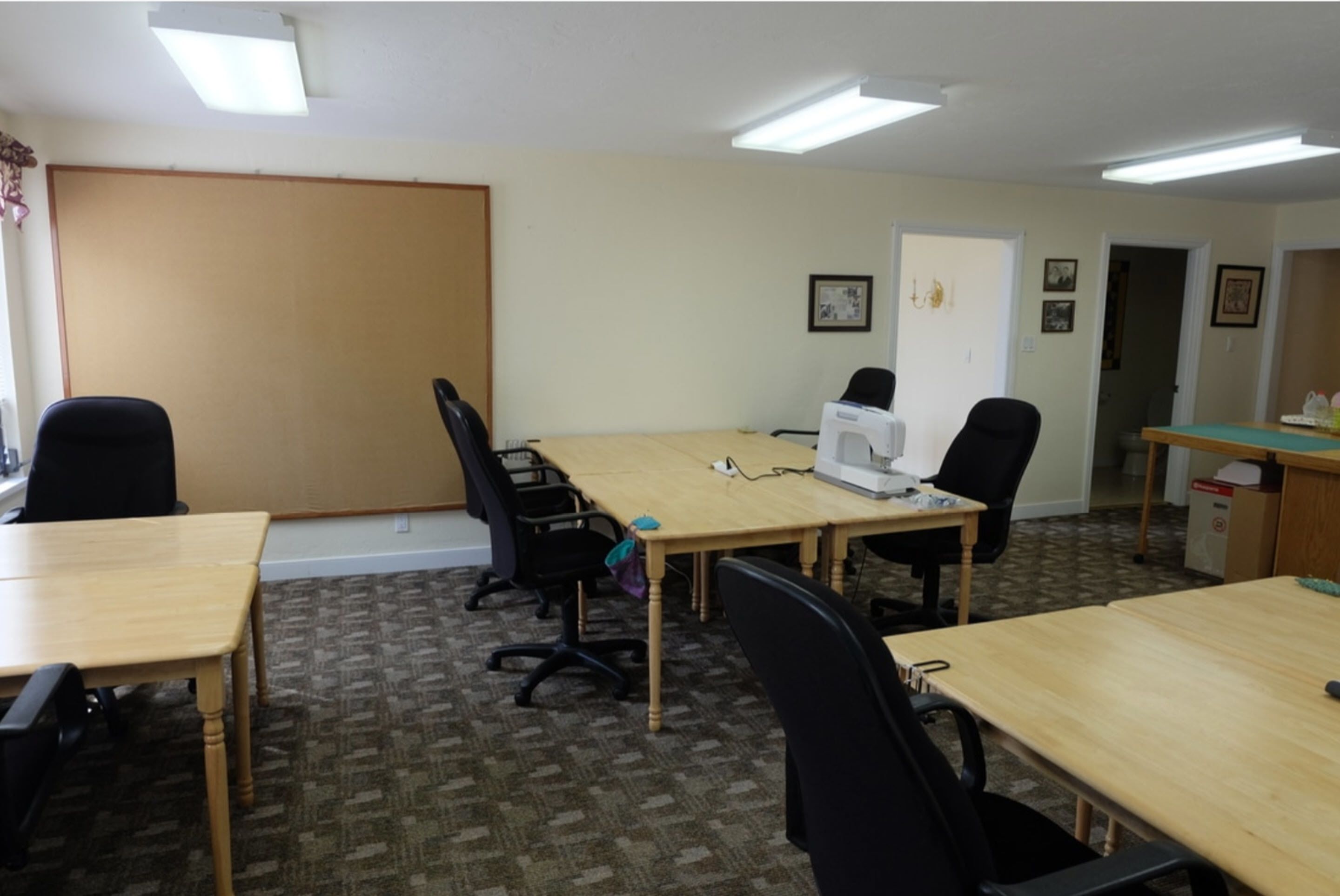 A conference room with a large table, four chairs, a projector, and a whiteboard.