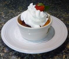 Un postre en un tazón blanco sobre un plato blanco con un encaje debajo.