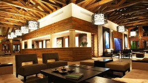 A modern lobby with wooden accents, seating areas, and pendant lighting.