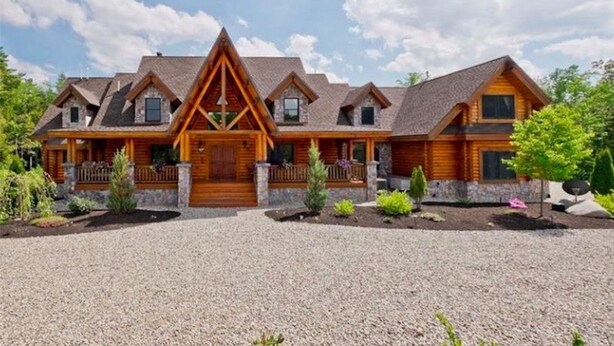 A large log cabin with a symmetrical facade, multiple windows, and a central entrance.
