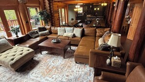 A log cabin interior with a living room, dining area, and kitchen.