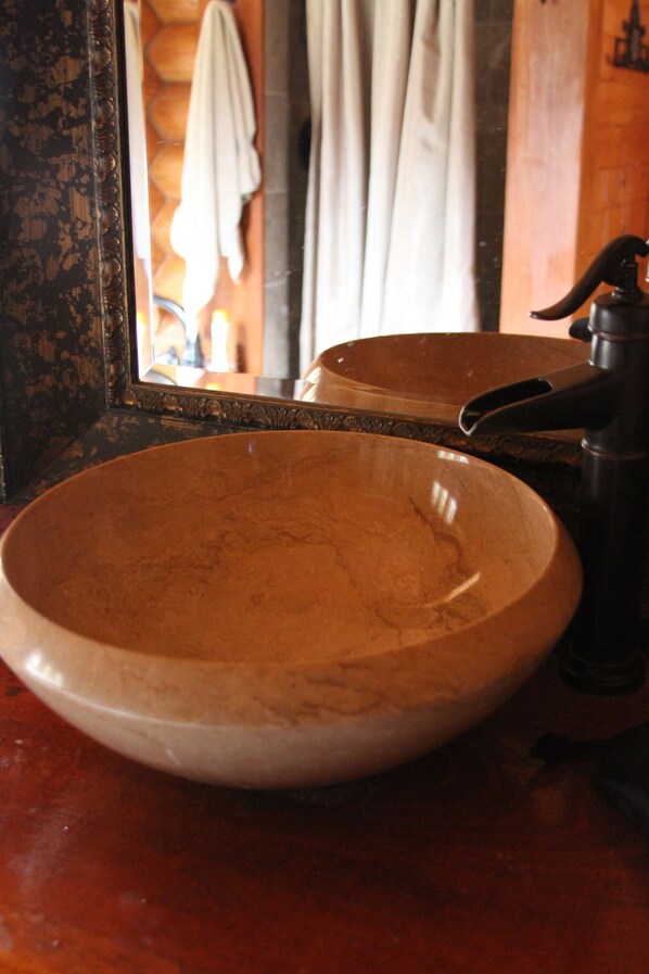 Un baño con lavamanos de madera, un espejo y una toalla colgada en la pared.