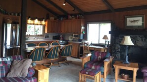 Interior acollidor d'una cabana amb zona de menjador, cuina i espai d'estar.
