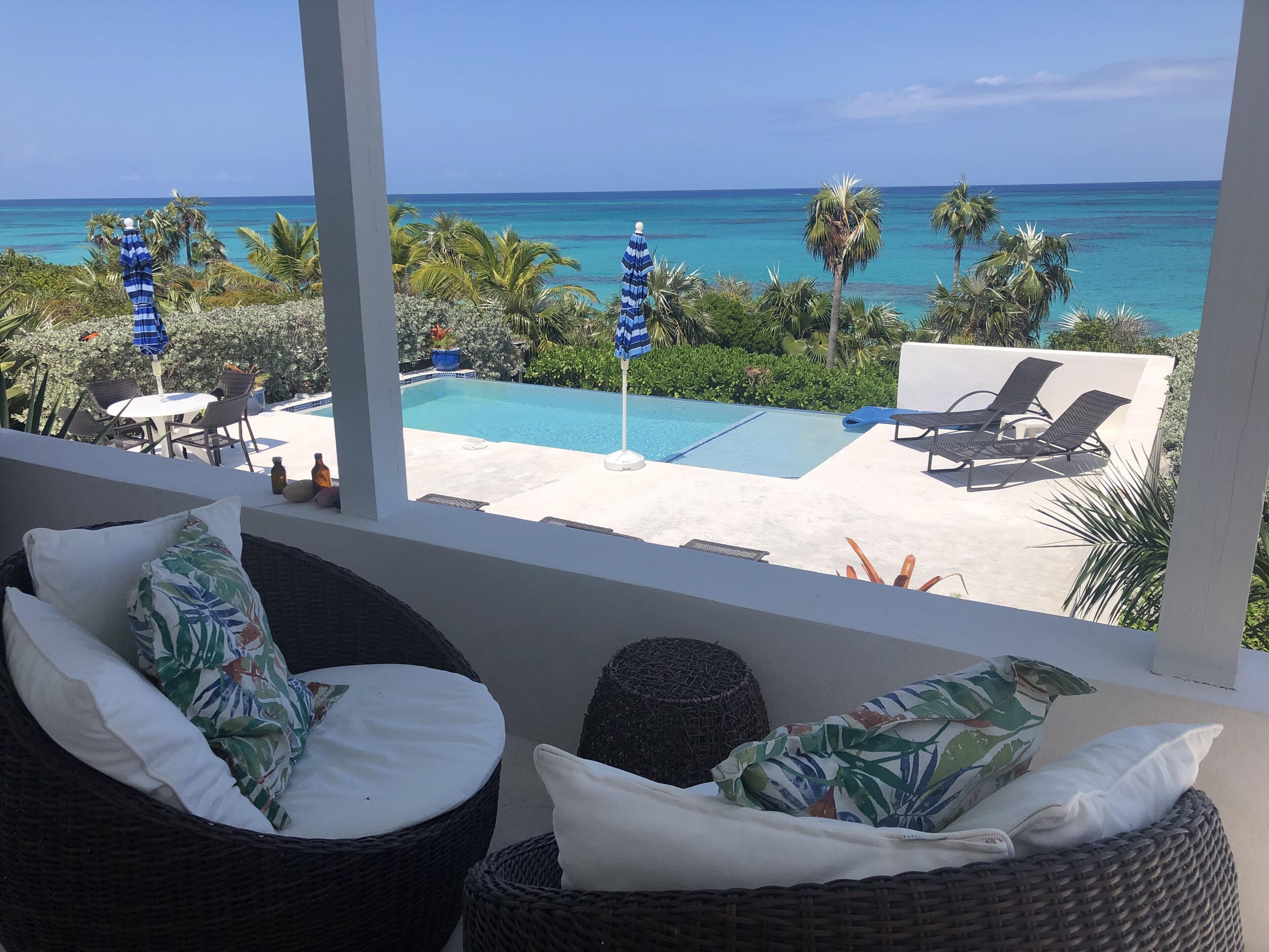 A balcony with wicker furniture, a pool, and a view of the ocean.