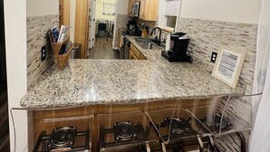 A kitchen with granite countertops, wooden cabinets, a stainless steel sink, and a built-in stove. - Tranquilla Villa. Bi Level Deck, HOT TUB, fire pit, grill, Movie & Game Rooms! (Tobyhanna)
