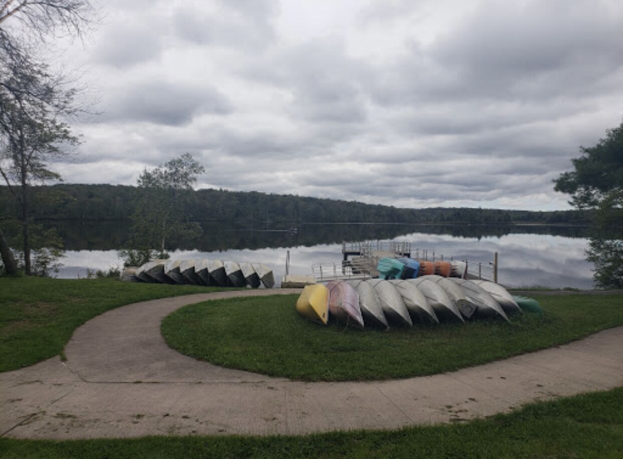 A lakeside path with canoes parked on the grass.