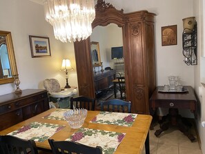 Un coin repas avec une table en bois, des chaises, un lustre et un miroir.
