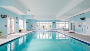 Una piscina interior con agua azul cristalina, rodeada de paredes azul claro y puertas blancas.