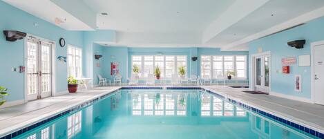 An indoor swimming pool with clear blue water, surrounded by light blue walls and white doors.