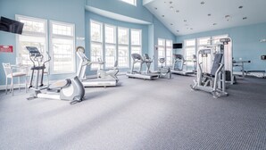 Un gimnasio con cintas de correr, elípticas y equipo de pesas.
