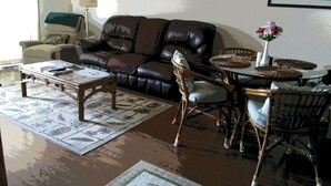 A living room with a leather sofa, a coffee table, a chair, and a small table with a vase of flowers.