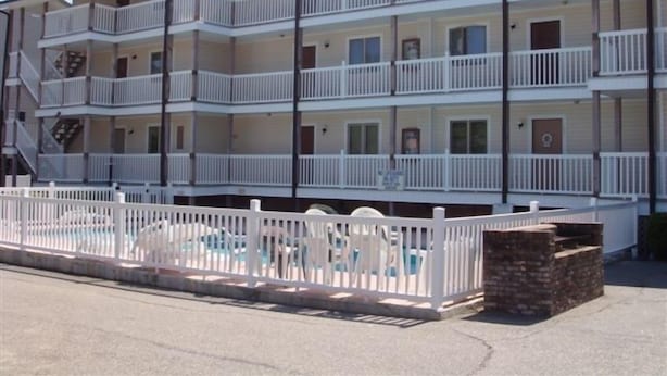 A multi-story motel with balconies, a pool area, and a brick structure.