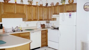 A kitchen with wooden cabinets, a white refrigerator, a coffee maker, and various kitchen appliances.