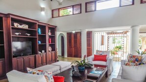A spacious living room with a television, white sofas, and a coffee table. - Villa Toscano by Casa de Campo Resort & Villas (La Romana)