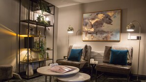 Una sala de estar moderna con un sofá, una mesa de centro redonda, una estantería y un cuadro en la pared.