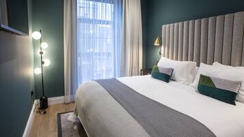 A hotel room with a large bed, a vanity with a mirror, and a window with curtains.