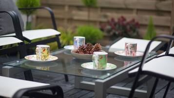 Ein Tisch mit Glasplatte, floral verzierter Tassen und Kiefernzapfen.