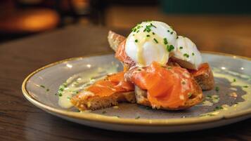 A plate with a dish consisting of smoked salmon, a poached egg, and chives on a slice of bread.