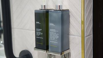 Two black bottles of Anyah body lotion on a metallic dispenser in a bathroom.