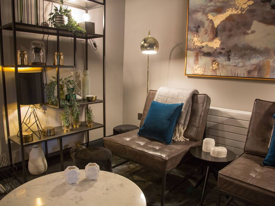 Ein moderner Lounge-Bereich mit Ledersofas, einem runden Tisch, einem Bücherregal und einem großen, abstrakten Gemälde an der Wand.