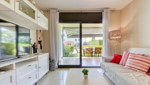 Una sala de estar moderna con un televisor de pantalla plana, un sofá blanco y una pequeña planta en maceta.
