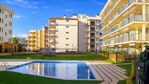 Un edificio residencial con piscina, balcones y un césped bien cuidado.