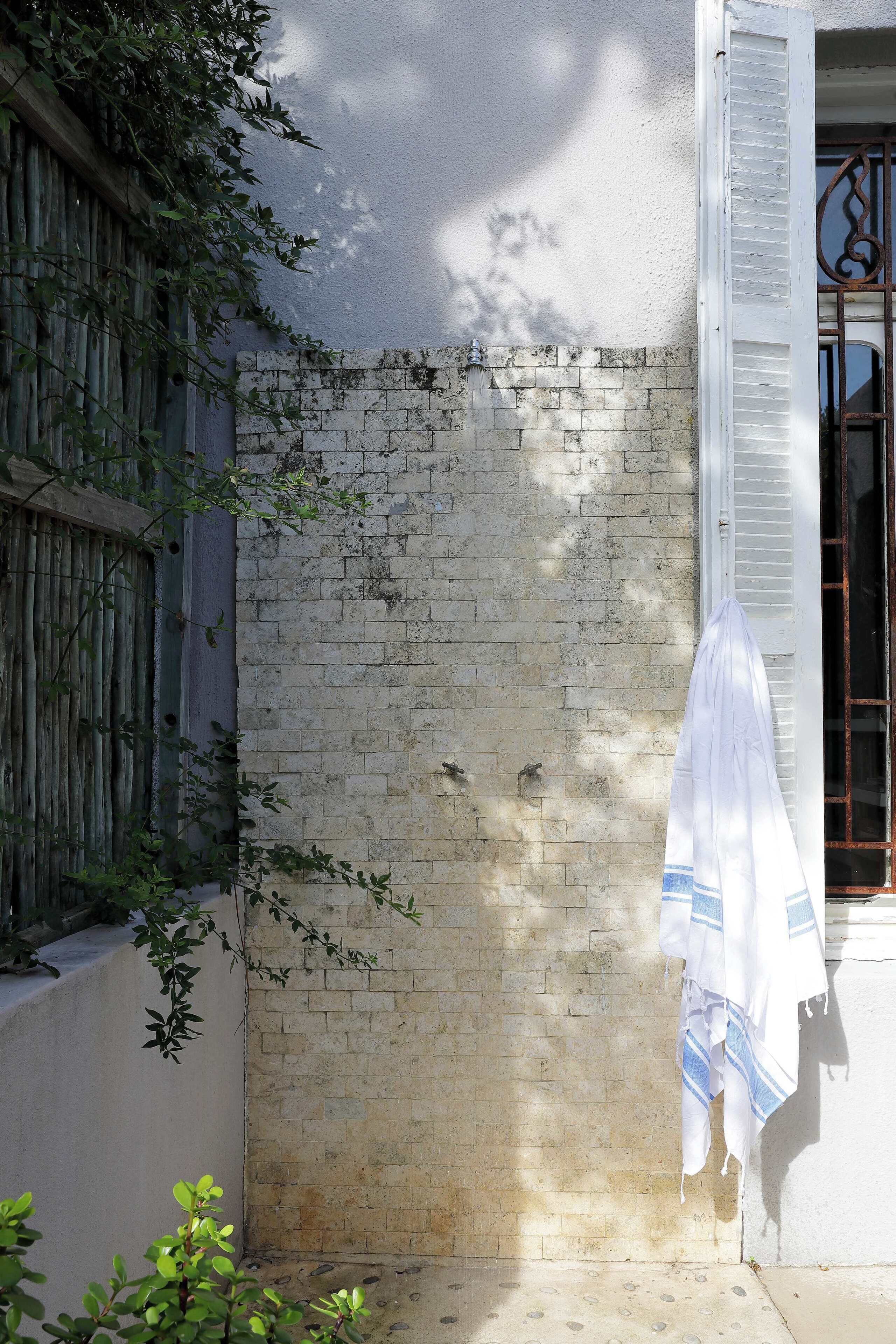 A corner of a building with a brick wall, a wooden fence, and a white towel hanging on the door.