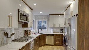 Una cocina moderna con armarios blancos, electrodomésticos de acero inoxidable y detalles de madera.