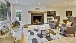 Una sala de estar moderna con chimenea, asientos cómodos y un ventanal grande.