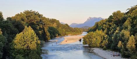 A river flanked by dense forests and mountains in the background.