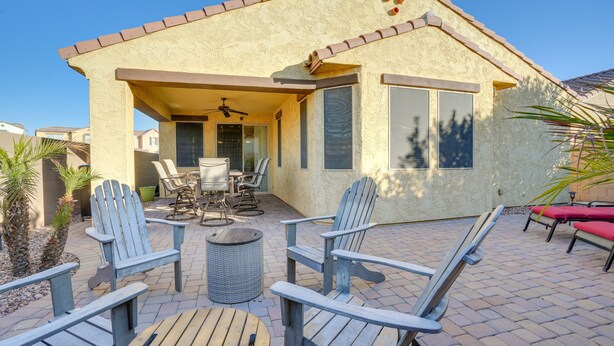 Una casa con patio amueblado con sillas Adirondack, una mesa y un ventilador de techo.
