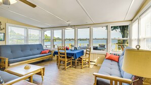 A sunroom with a view of the sea, furnished with a sofa, chairs, and a dining table. - Bayfront Red Creek Vacation Rental w/ Boat Dock! (Red Creek)