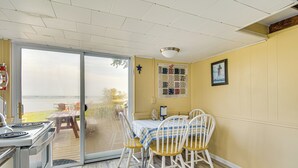 A dining area with a table and chairs, a view through a glass door to an outdoor deck, and a fire extinguisher mounted on the wall. - Bayfront Red Creek Vacation Rental w/ Boat Dock! (Red Creek)