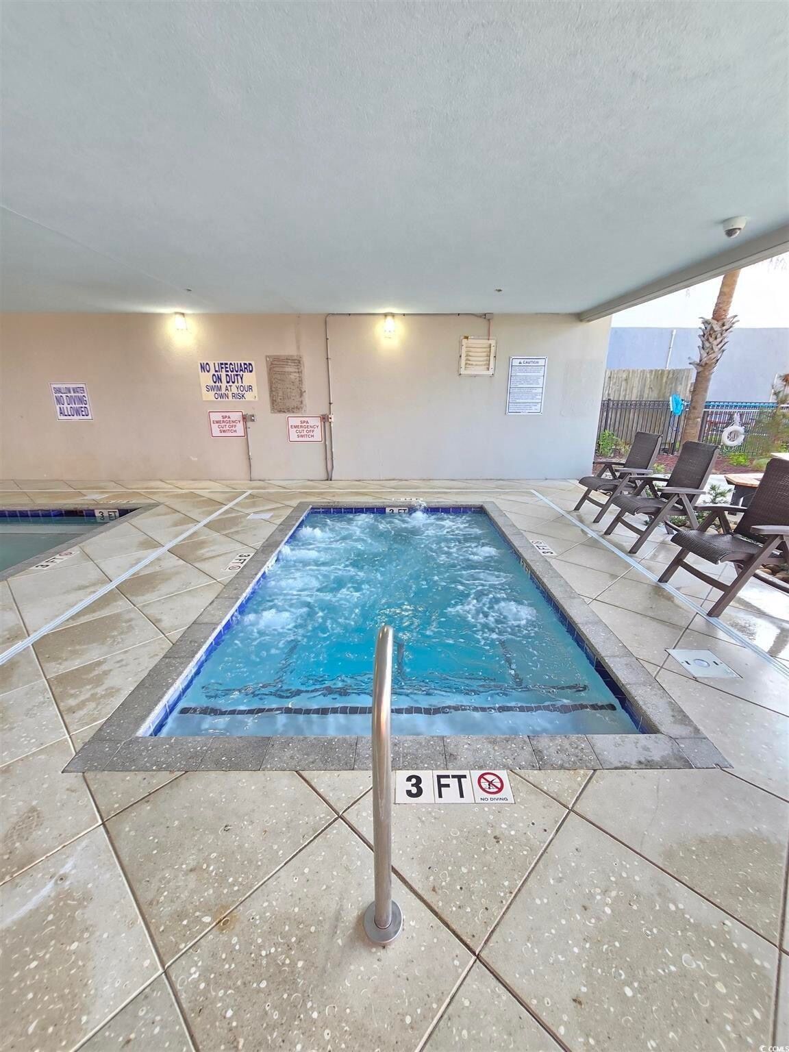 Une piscine dont la profondeur est indiquée à 3 pieds, avec des chaises longues et des panneaux de sécurité fixés aux murs.