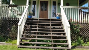 Une maison à deux étages avec un porche à l’avant, une porte en bois et le numéro « 1203 » sur la porte.