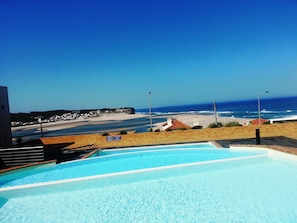 En swimmingpool med utsikt över stranden och havet.