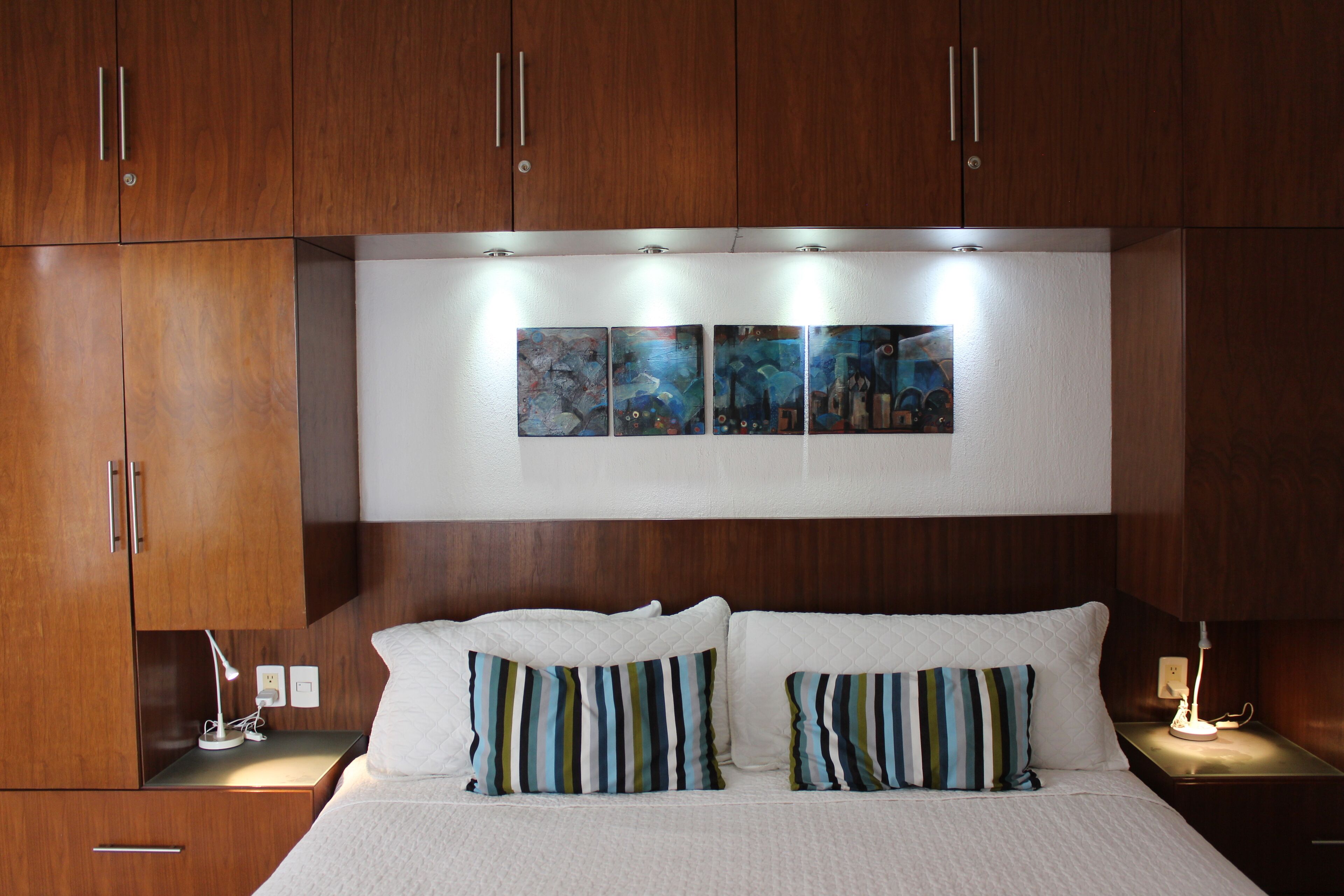 A bedroom with a bed, two bedside tables, a nightstand, and a wall-mounted artwork above the bed.